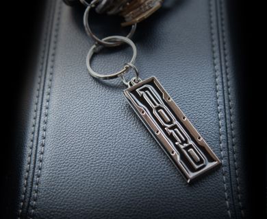 Metal Ford Keychain laying on a leather background